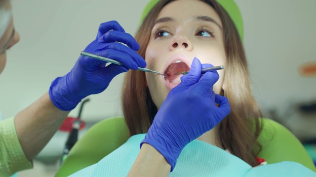 女牙医用牙科工具检查病人的牙齿。医疗视频素材