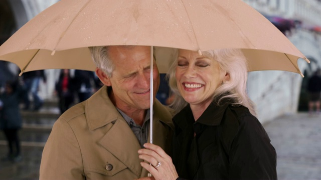 在罗马，一对成年夫妇在雨伞下挤作一团视频下载