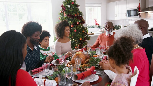多代混血儿家庭坐在圣诞餐桌上手牵着手说感恩，有选择的重点视频素材