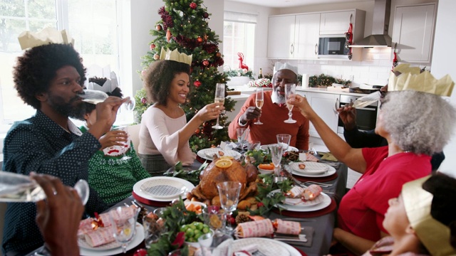 黑人祖父站在家庭圣诞餐桌上发表讲话并敬酒，正面视频素材