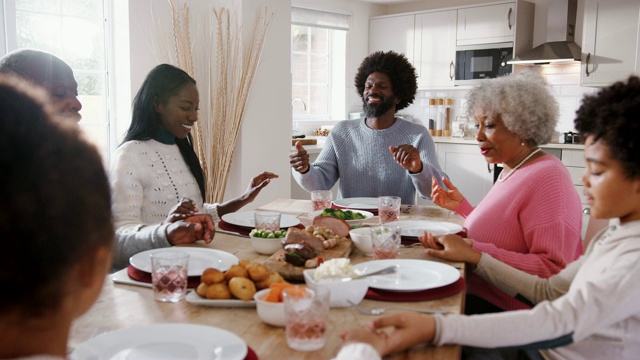 多代混血儿家庭手牵着手，在吃他们的周日晚餐前在餐桌上祷告，有选择的焦点视频素材