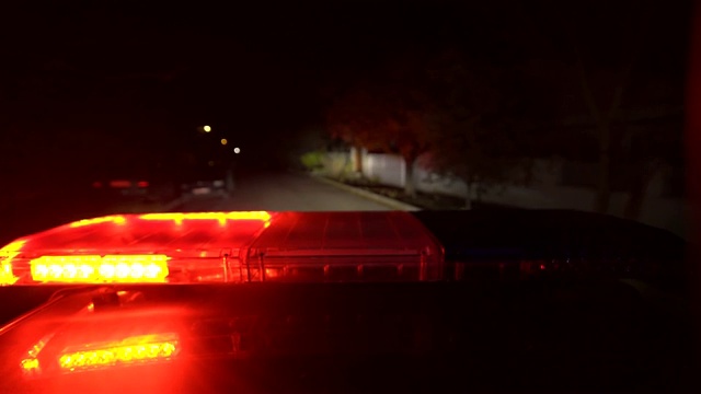 驾驶夜间有红蓝警灯闪烁的警车视频素材