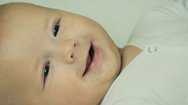 一个快乐的新生儿在镜头前微笑的慢动作特写。视频下载