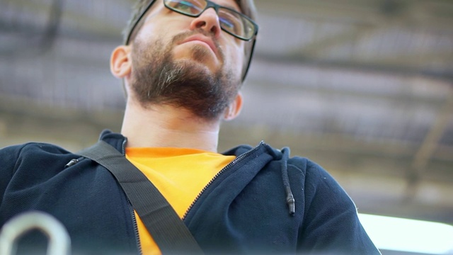 一个留着胡子戴着眼镜的男人走进一家超市。他在购物车附近等着。视频素材
