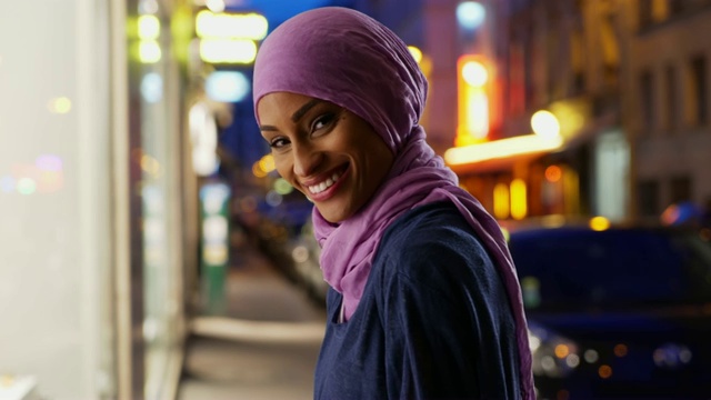 美丽的年轻穆斯林女子在城市背景下，对着镜头微笑视频下载
