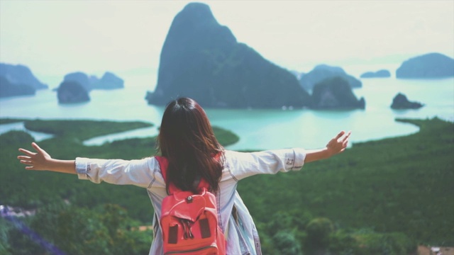 迷人的亚洲女游客在山顶举起手臂看风景，感受自由和享受自然的4K慢镜头，在相同的Nang Chee，旅行和幸福的生活理念视频素材