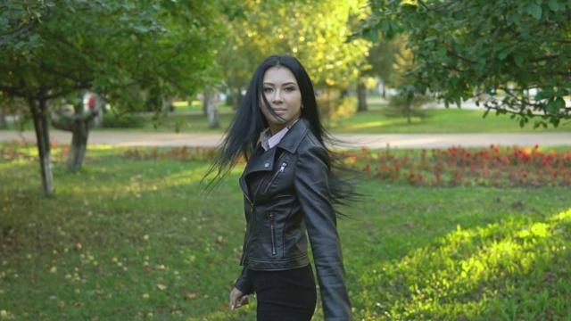 年轻美丽的女孩走在阳光明媚的夏日公园的背景上转身视频素材