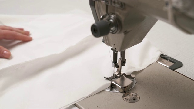 缝纫机缝白色织物的特写镜头。女人的手在为婚纱缝制它视频素材