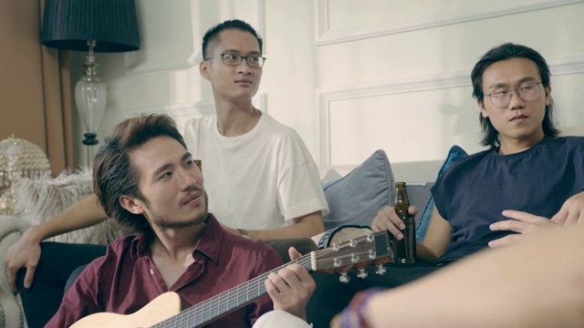 一群年轻的亚洲音乐家聚在家里喝啤酒视频素材