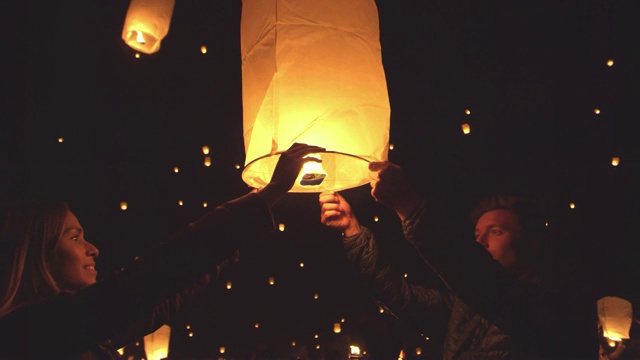 快乐的年轻夫妇在节日的晚上燃放火红的灯笼视频素材
