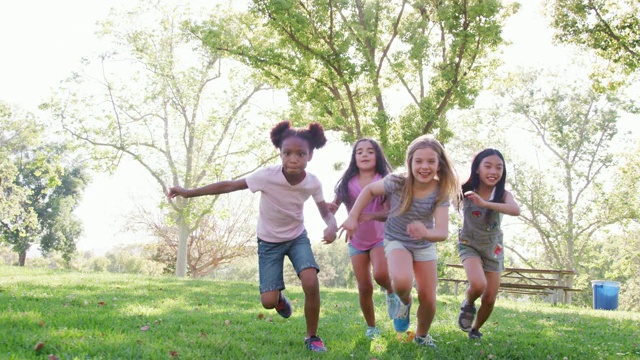 一群年轻女孩和朋友在公园里踢足球，慢动作拍摄视频素材