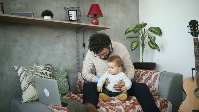 父亲和小儿子在电脑上看动画片视频素材