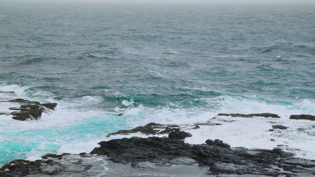 海浪冲上碧绿卡波的黑色火山岩的4k视频片段视频素材
