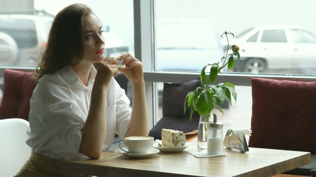一个年轻漂亮的女人在咖啡馆喝咖啡。年轻女子在午餐时间穿着职业装视频素材