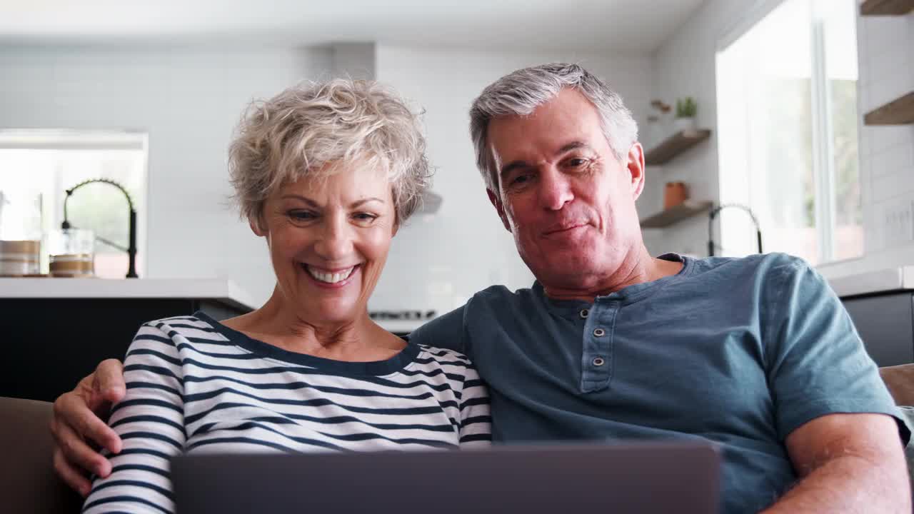 老夫妻在笔记本电脑上视频通话，对着屏幕挥手视频素材