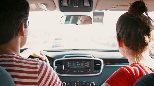 一对年轻的白人夫妇在高速公路上开车，后视镜，特写视频素材