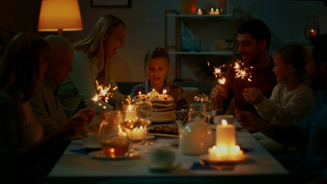 可爱的小女孩在餐桌上庆祝生日，妈妈带来蛋糕，女孩吹灭蜡烛。在餐桌上，亲朋好友欢聚一堂。视频素材