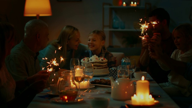 在家人和朋友的陪伴下，在餐桌上庆祝可爱的小女孩的生日。女儿，妈妈和爸爸试图吹灭蛋糕上的蜡烛。庆祝生日快乐。视频素材