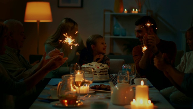 可爱的小女孩在餐桌上庆祝生日，妈妈带来蛋糕，女孩吹灭蜡烛。在餐桌上，亲朋好友欢聚一堂。视频素材