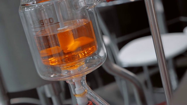 在化学实验室里，混合着黄色液体的玻璃烧瓶视频素材