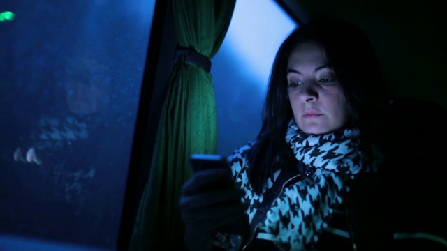 晚上乘靠窗的公交车时使用手机的女子视频素材