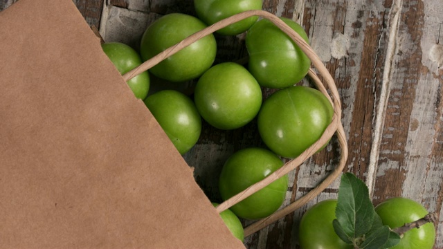 购物袋里的一组青梅水果放在一张木桌上视频素材