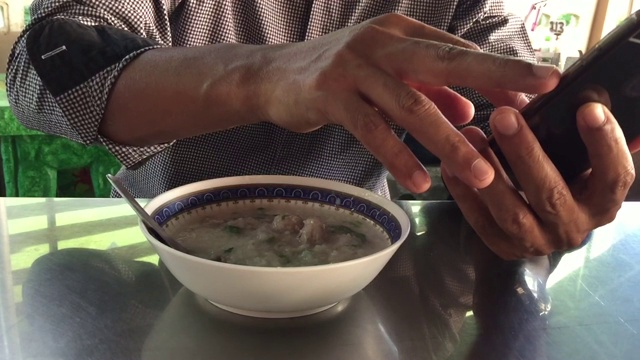 特写一名亚洲男子正在吃一碗猪肉粥视频素材