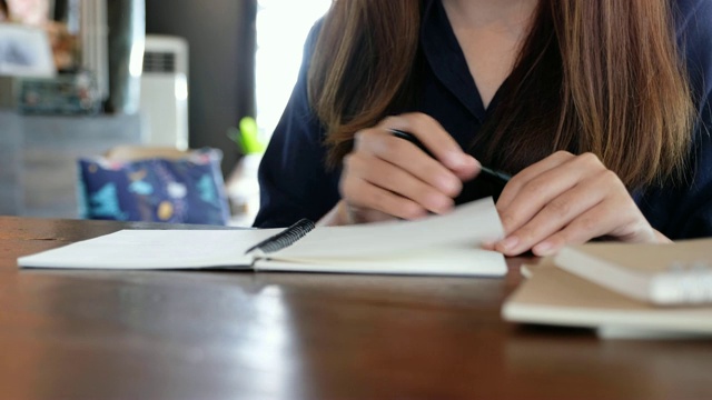 特写图像的一个女人打开一个空白笔记本写在木桌上视频素材