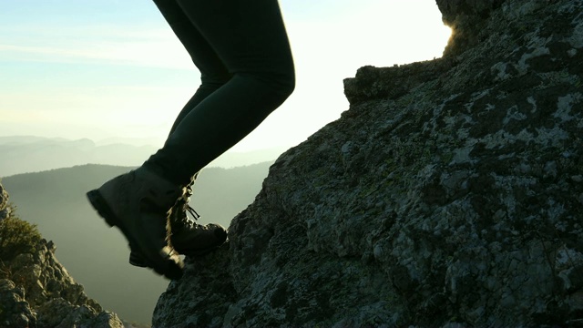 女人的腿攀登岩石尖顶与戏剧性的背后视频下载