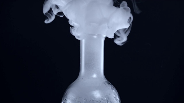 在黑色背景和相反的情况下，干冰的烟雾和水从烧瓶中泄漏视频素材