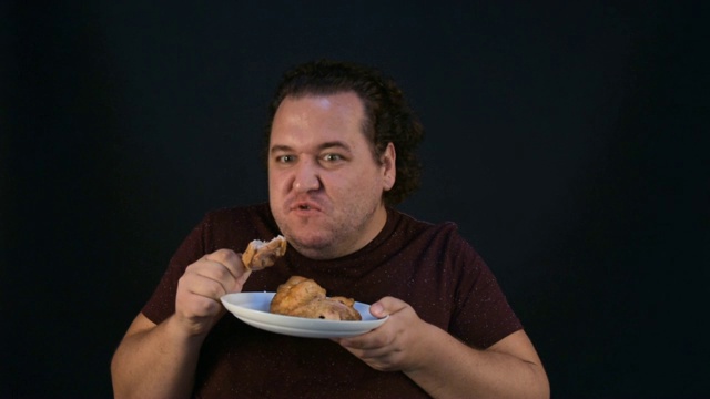 那个胖子吃肉吃得很贪婪。视频素材