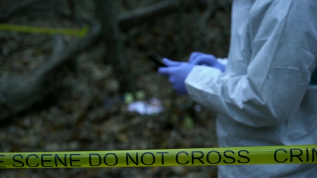 犯罪实验室的现场工作人员在森林里的犯罪现场输入平板电脑数据视频下载