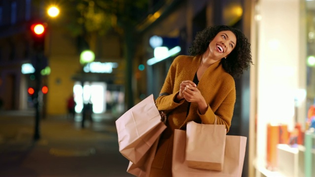 时尚的黑人妇女晚上在城里购物时愉快地跳舞视频素材