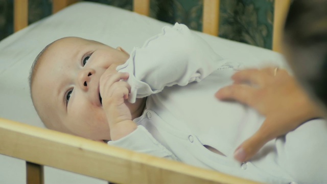 妈妈用慢动作逗弄躺在婴儿床里六个月大的婴儿。视频素材