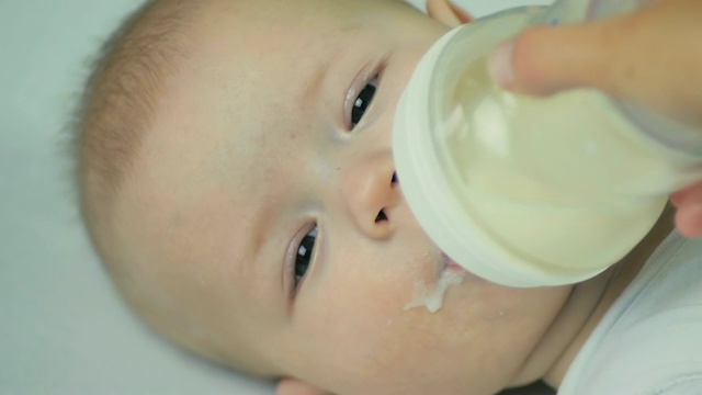 特写母亲用手从奶瓶里喂新生儿牛奶。视频素材