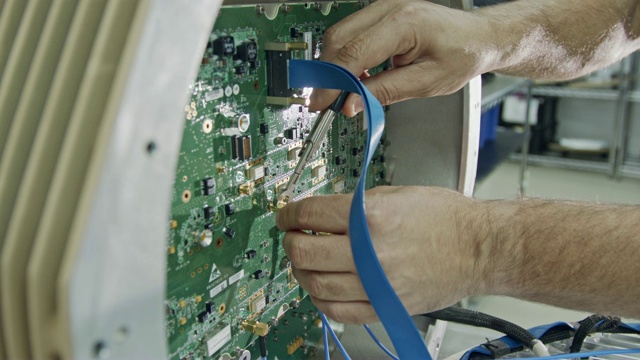 靠近工人的手连接电线到一个大电路板视频素材