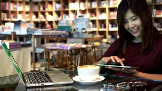 4k镜头的场景特写亚洲女商人使用平板电脑和绿色屏幕的笔记本电脑，在咖啡馆喝咖啡，生活方式和商业概念视频素材