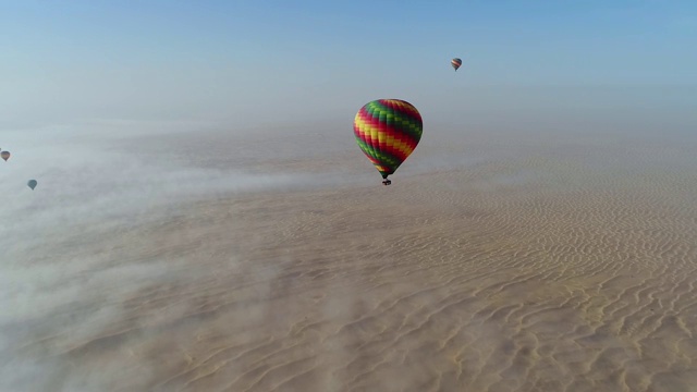 热气球在沙漠云层中飞行的鸟瞰图迪拜，阿联酋视频购买