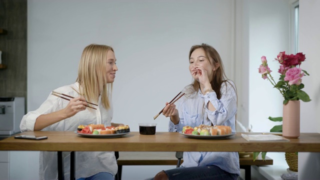 两个可爱的年轻女孩吃寿司卷和聊天，朋友一起在厨房视频素材