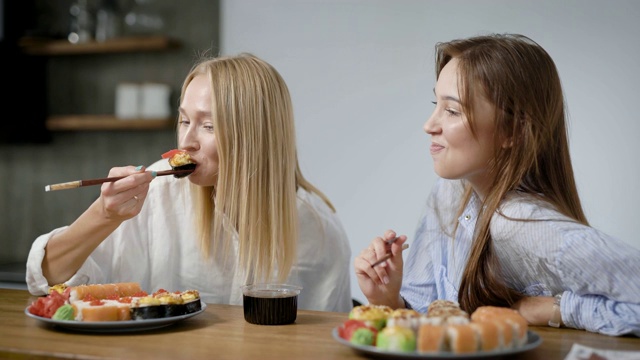 两个漂亮的女孩在家吃日本菜。卷在盘子里是不一样的，很好吃视频素材