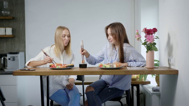 两个年轻女人在家里聊天吃寿司，最好的朋友一起度过时间视频素材