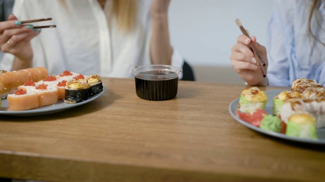 两盘不同寿司卷的特写镜头，女孩用筷子吃寿司视频素材