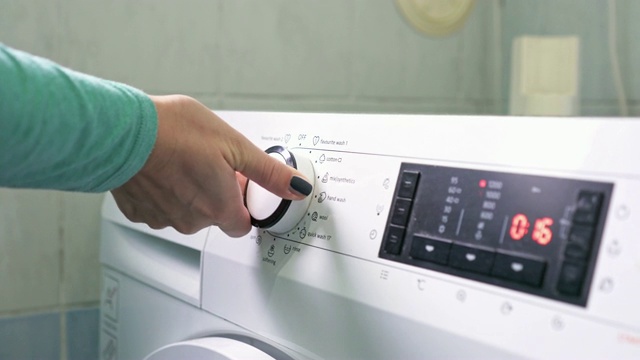 一个女人在给洗衣机设置程序视频素材