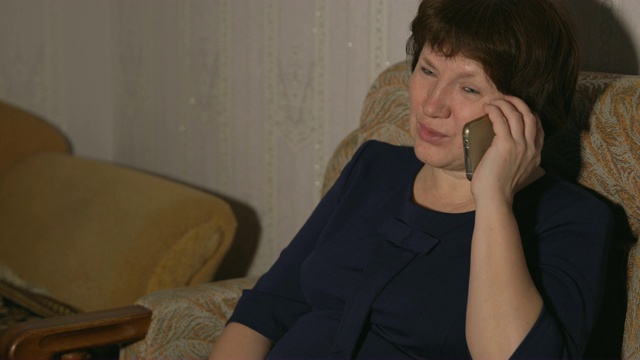 一个穿着蓝色裙子的女人正坐在椅子上打电话视频素材