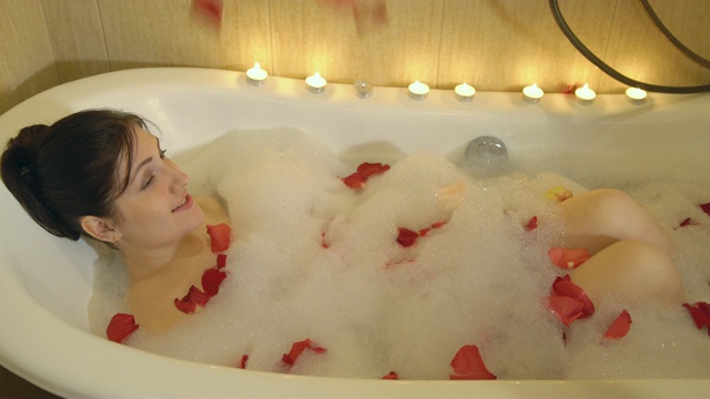 一个黑发女人正在用泡沫和玫瑰花瓣洗澡视频下载