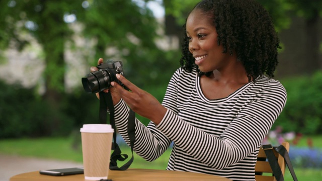 可爱的黑人妇女坐在美丽的花园在布鲁日用相机拍照视频下载