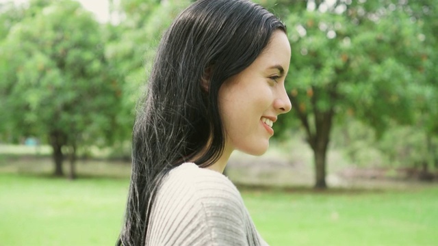 一个年轻女人在公园呼吸新鲜空气放松的侧视图肖像视频下载