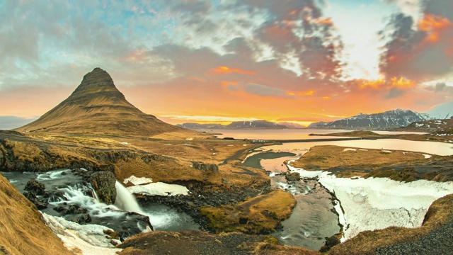 从冰岛的Kirkjufell看到的五颜六色的日出布满了天空。阳光的金色光芒反射在海洋中。视频下载