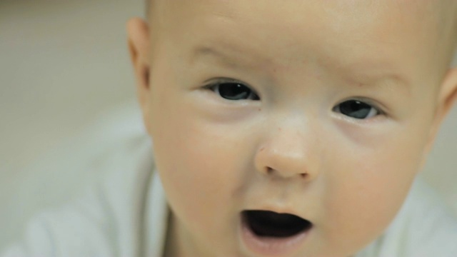 一个快乐的5个月大的婴儿看着镜头微笑的慢动作特写。视频素材