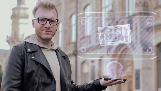 聪明的年轻人戴着眼镜展示了一个概念全息图袖珍相机视频素材
